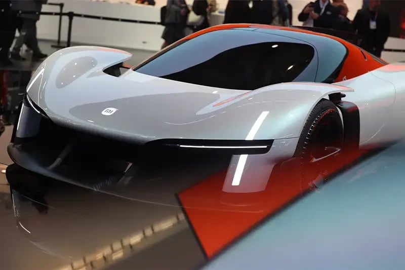 Futuristic Xiaomi electric concept sports car with a sleek silver and orange aerodynamic design displayed at a technology exhibition.
